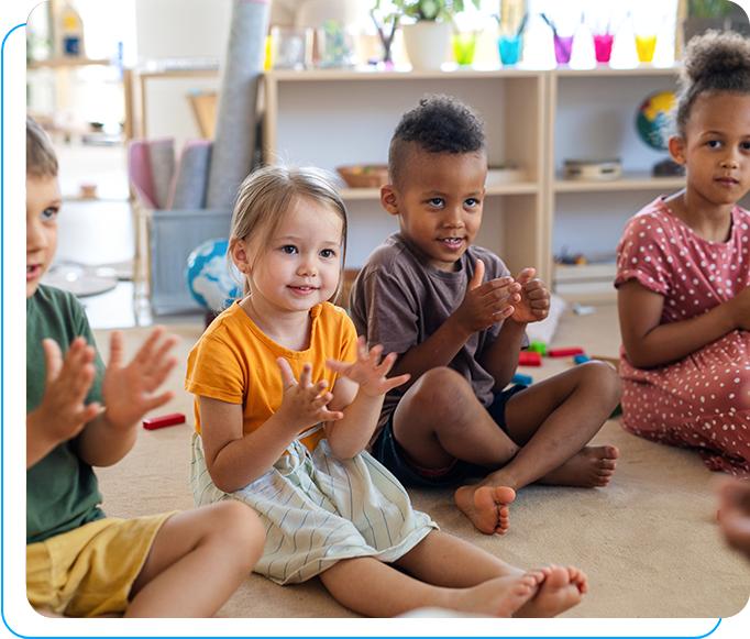 A group of children sitting on the floor clapping.