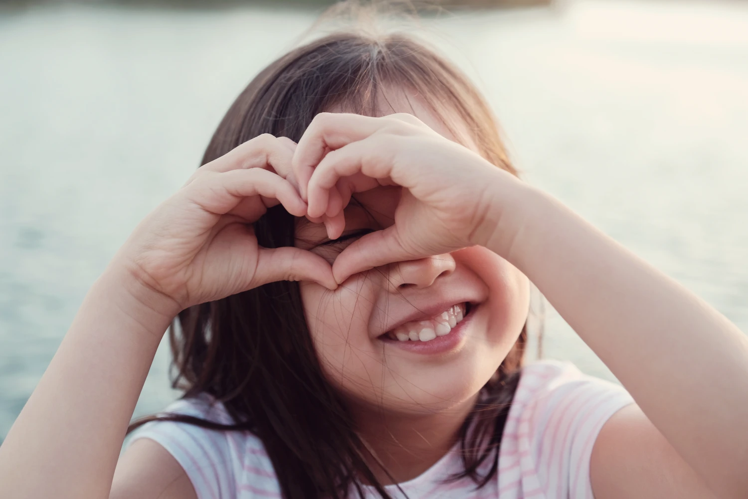 A girl making a heart with her hands.