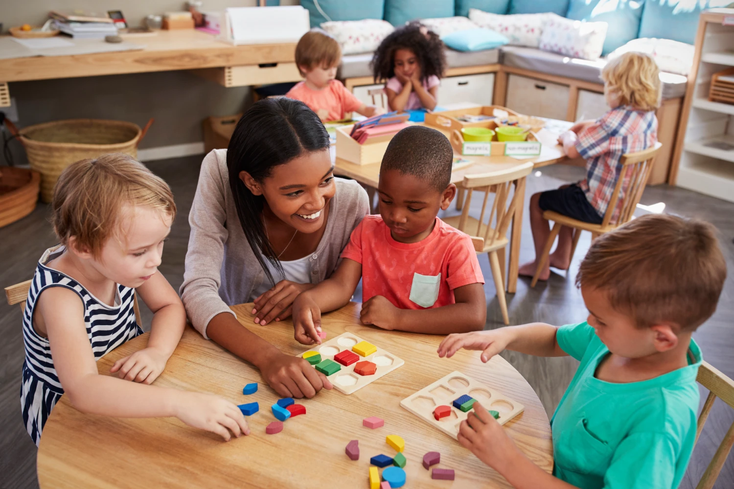 A group of children sitting at a table playing with blocks.